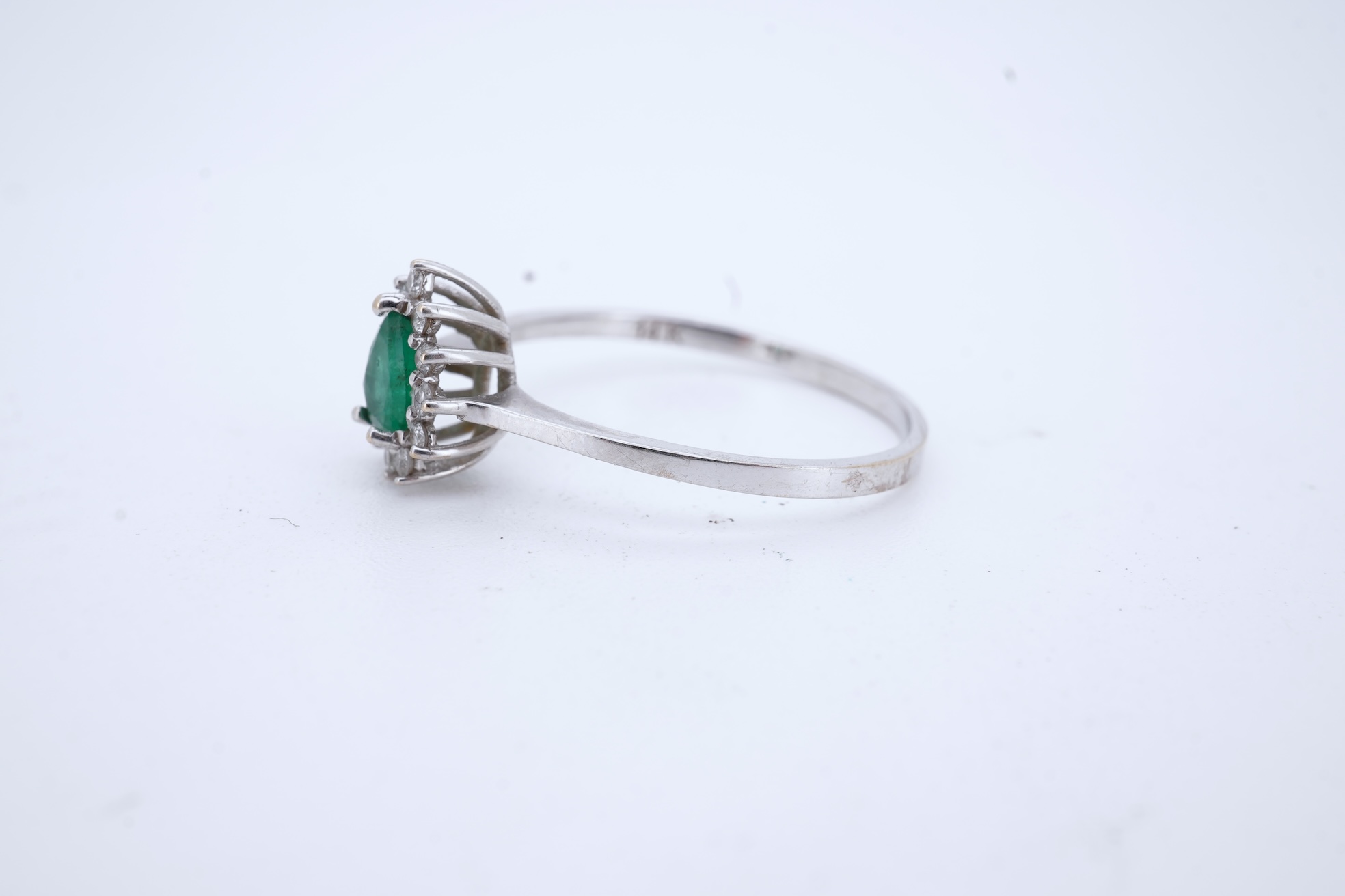 A modern white metal(stamped 14k), emerald and diamond set pear shaped cluster ring, size R, gross weight 1.3 grams.